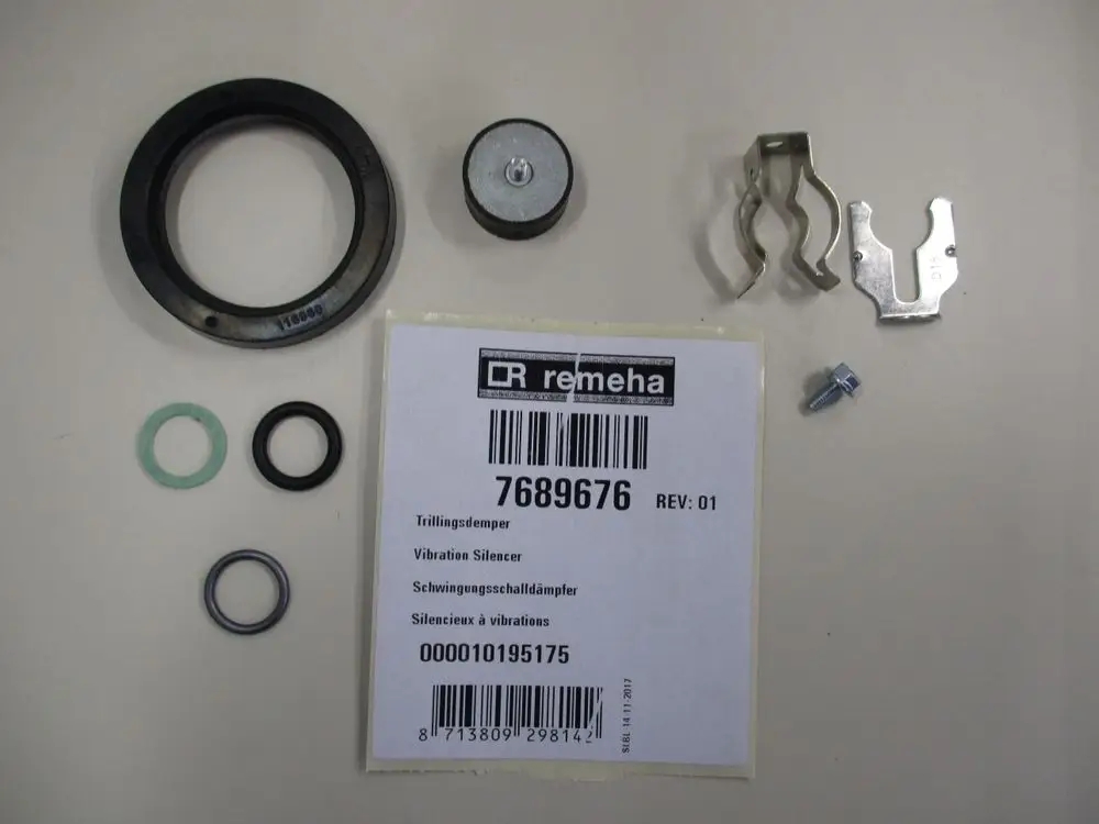 Remeha Teile mit einem Vibration Silencer, Gummiringen, Metallclips und Schraube, die auf einem hellen Hintergrund angeordnet sind.
